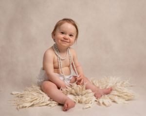 Baby girl wearing pearls, first birthday photograph