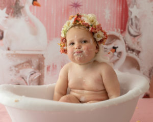 Baby wearing flower bonnet in bath tub