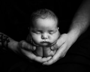 Newborn baby cradled in dad's hands
