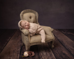 Baby girl sleeps on chair wearing knitted romper